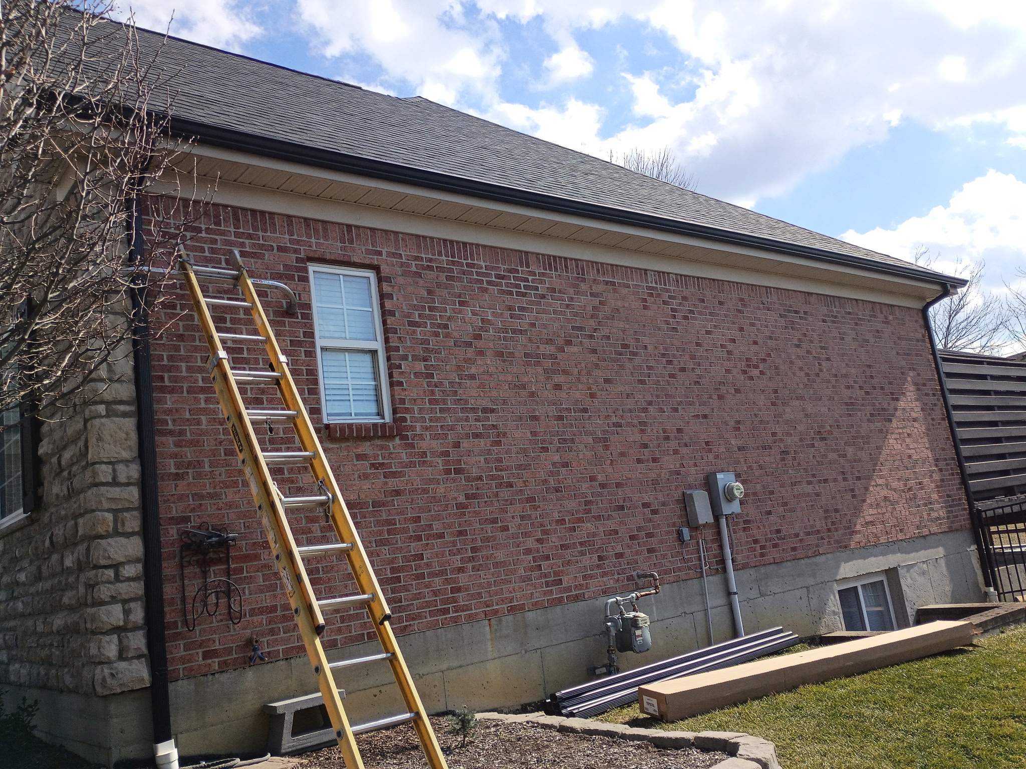 Gutter materials staged beside a brick home during gutter replacement