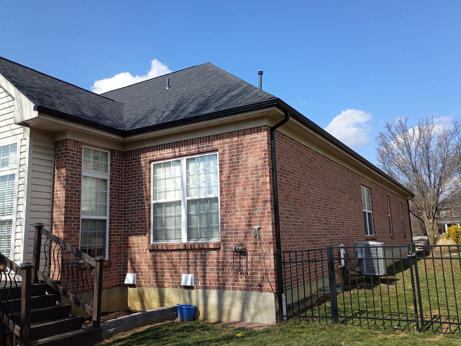 Black gutter and downspout on a brick home after gutter repair