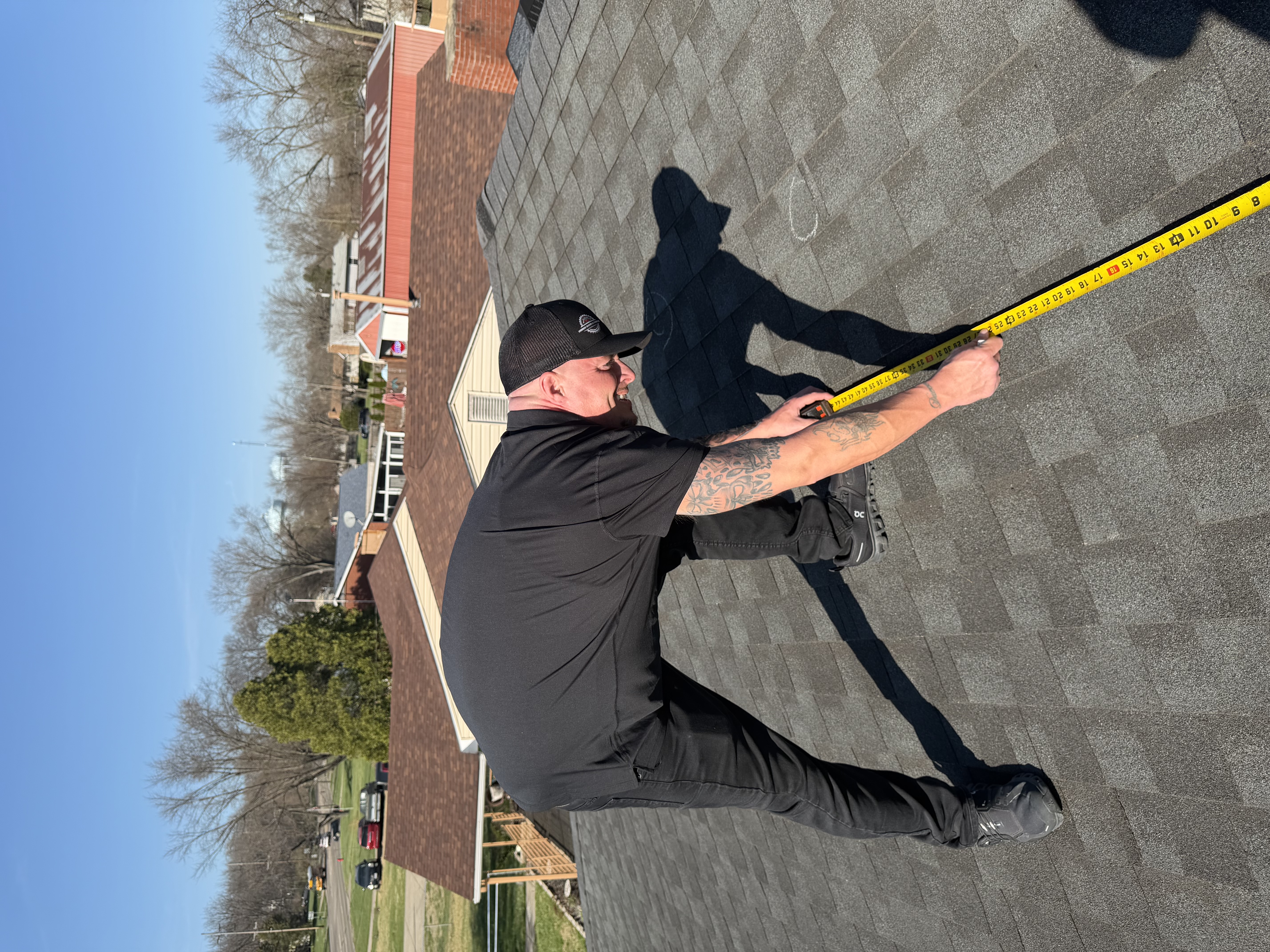 Roofer measuring asphalt shingles during a residential roof inspection