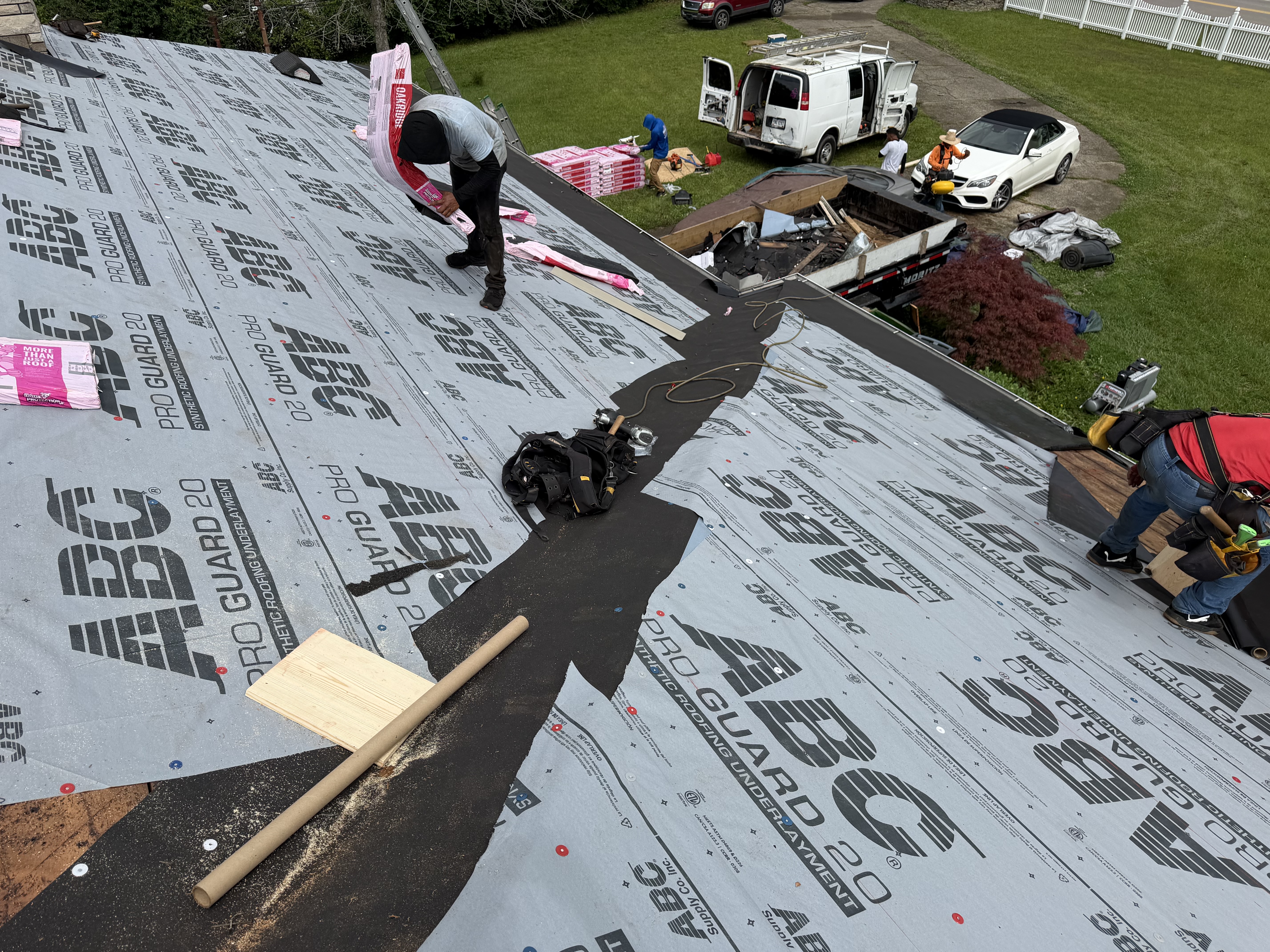 Crew installing underlayment and staging shingles during a full roof replacement