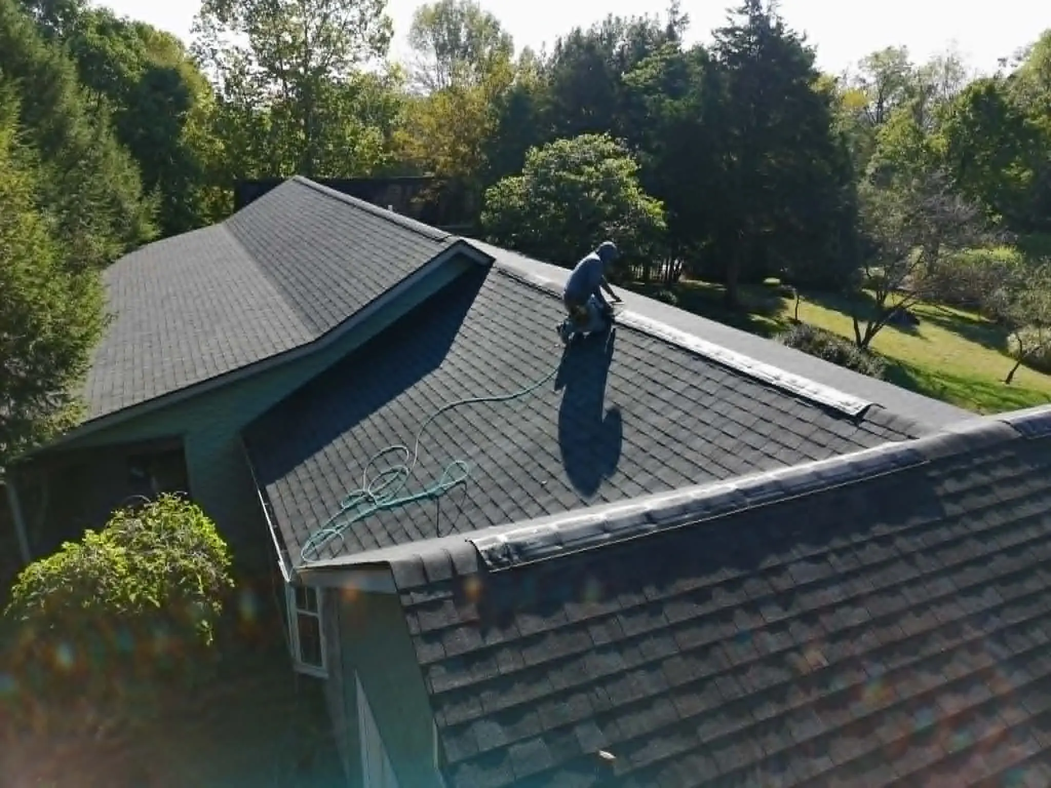 Roofing contractor installing shingles on a residential home roof
