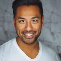 Smiling man with a beard wearing a white V-neck shirt